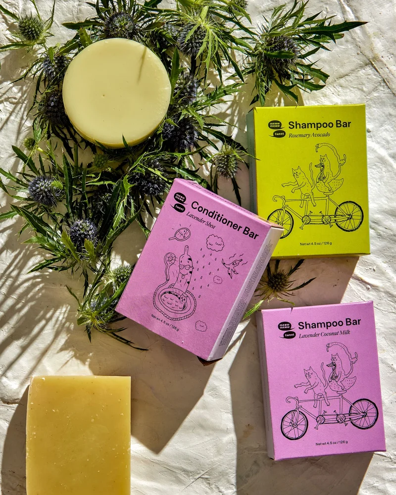 A collection of shampoo and conditioner bars haphazardly arranged with wildflowers