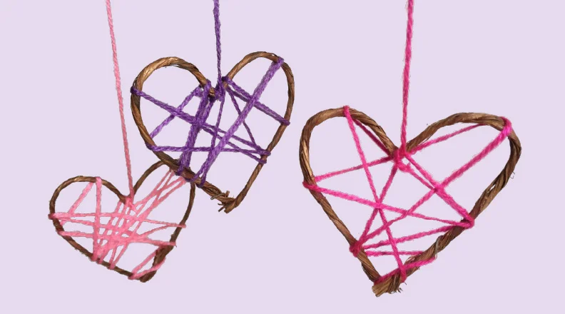 Two handmade string heart dreamcatchers hanging on display.