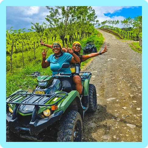 Image description: Two travelers with helmets making peace signs while sitting on an ATV