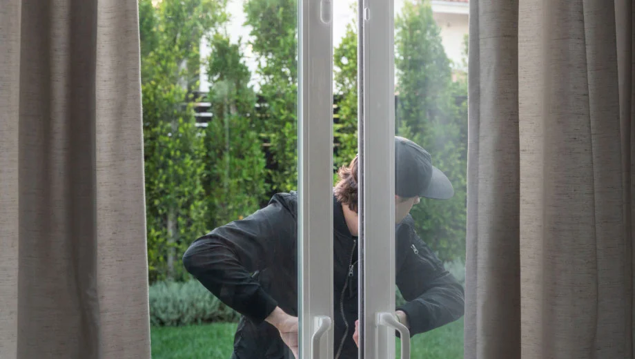 Burglar entering home through door with Arlo All-in-One Sensors.