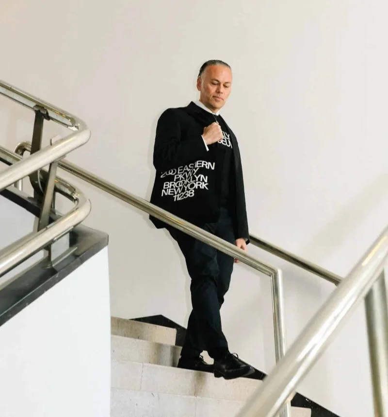 Man walking down stairs holding a Brooklyn Museum tote bag