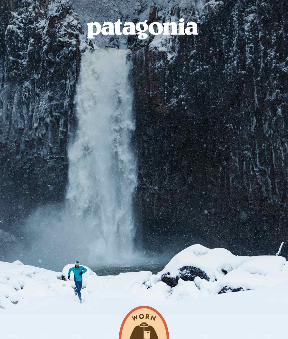 Patagonia. A person running in the snow near a waterfall.