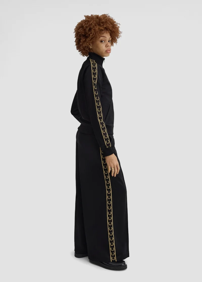 Woman model wearing the Fred Perry Taped Track Jacket and Track Pants in Black / Champagne