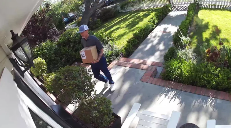 View of a package delivery at the front door of a home from the view of an Arlo Essential Wireless Security Camera.