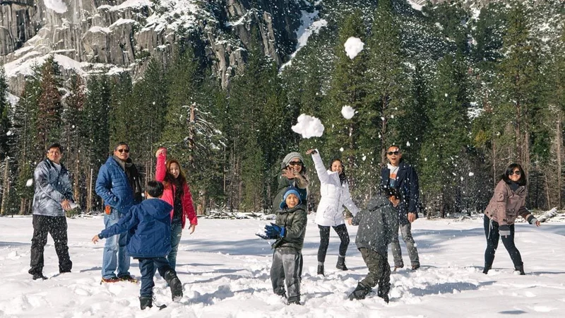 Image description: A family taking pictures and playing in snow at Yosemite National Park during winter.