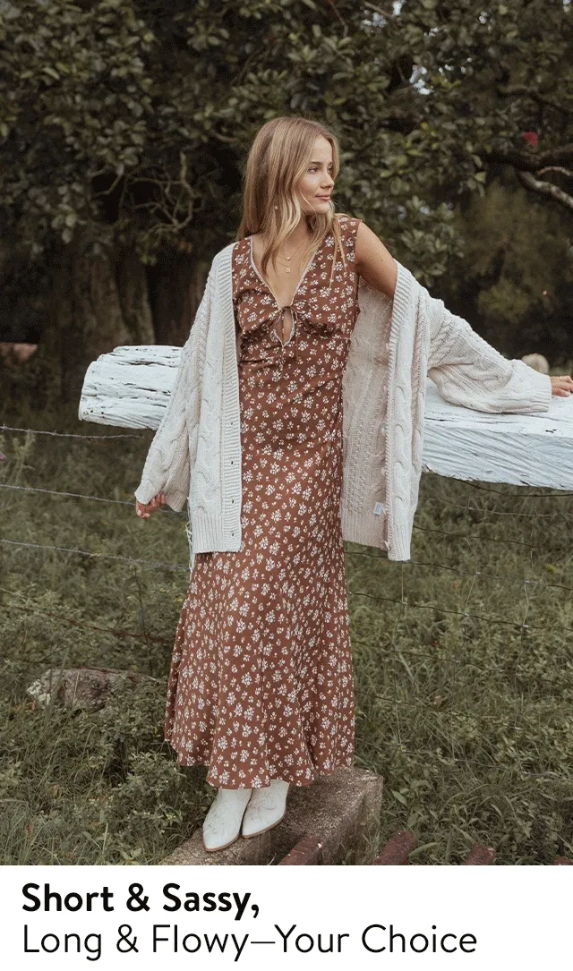 A woman wearing a floral maxi dress with a cardigan and boots.