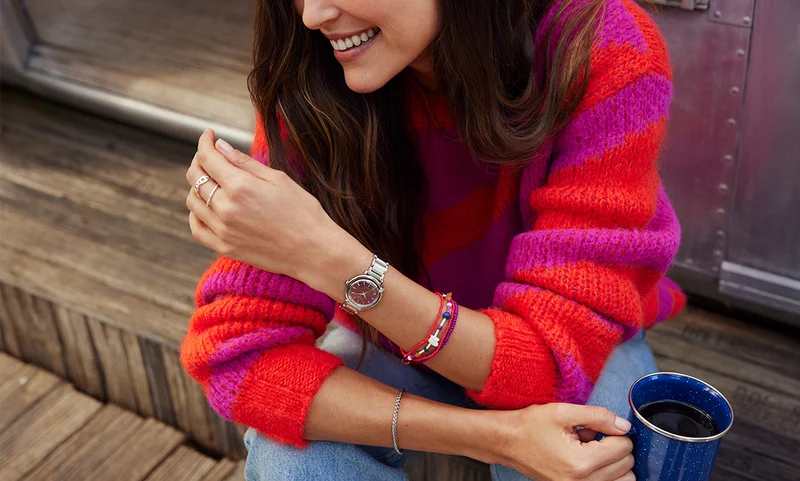 A women sitting outside with a cup of coffee and wearing the exclusive red dial Citizen L Arcly