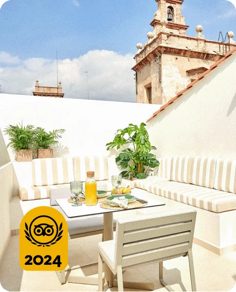 Image Description: White tables and chairs on a white patio. A breakfast spread with juice is on the table. A gold 2024 Travelers’ Choice Awards Best of the Best badge is on the bottom left corner of the image.