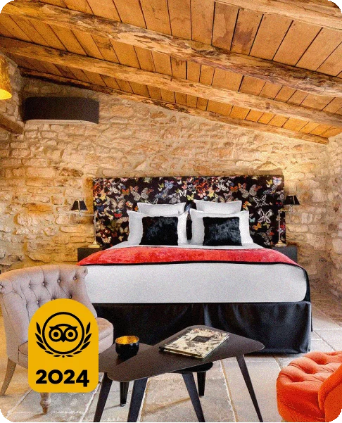 Image Description: A bed with a red throw blanket and a butterfly-printed headboard in a rustic room. A gold 2024 Travelers’ Choice Awards Best of the Best badge is on the bottom left corner of the image.