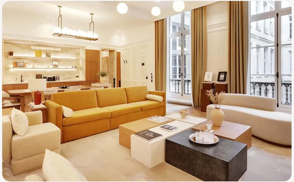 Bright living room with sofas, tables, and large windows opening onto a balcony.