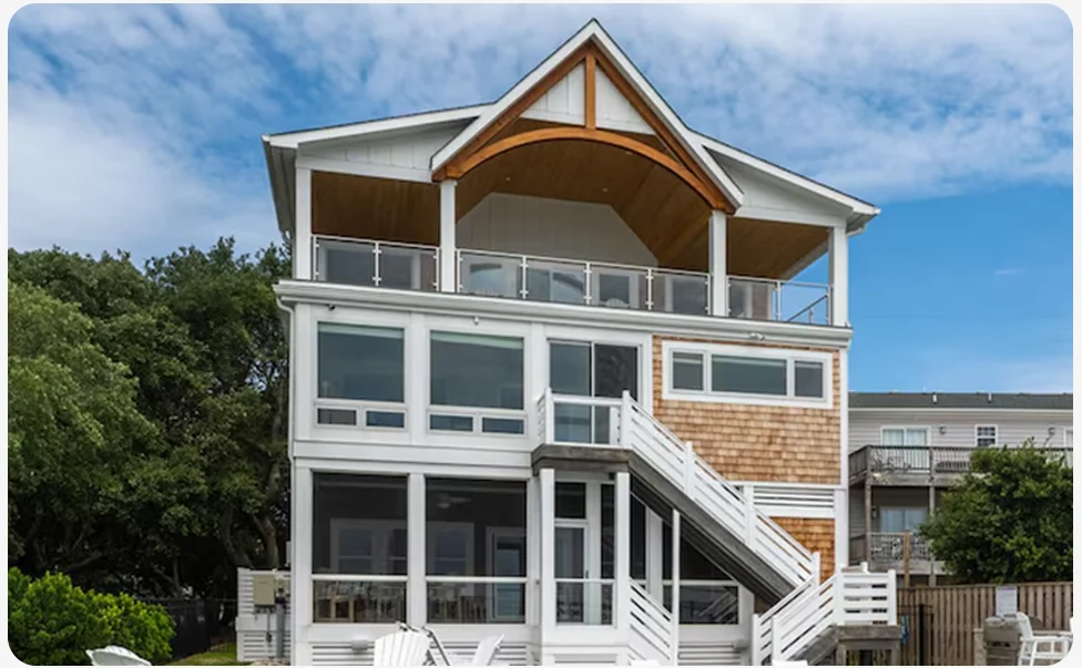 Multi‑storey home with balconies and a pool, shown with outdoor seating and landscaped surroundings.