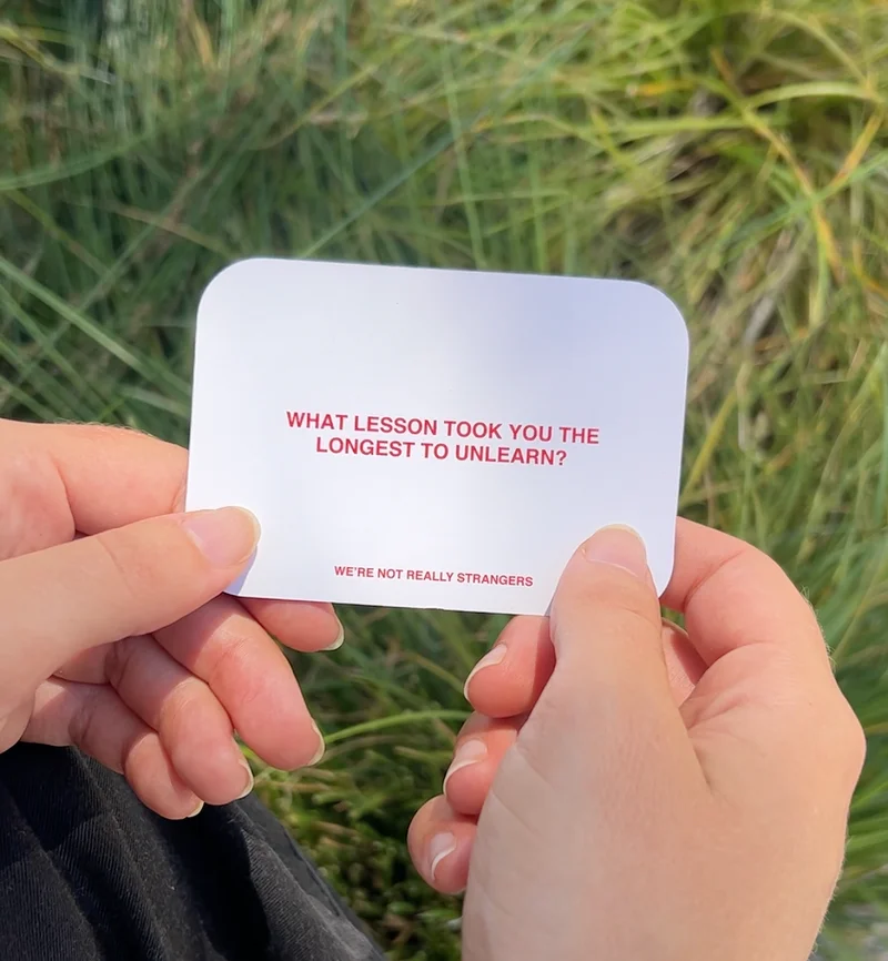 Image of someone playing We're Not Really Strangers Card Game holding card reading "what lesson took you the longest to unlearn?"