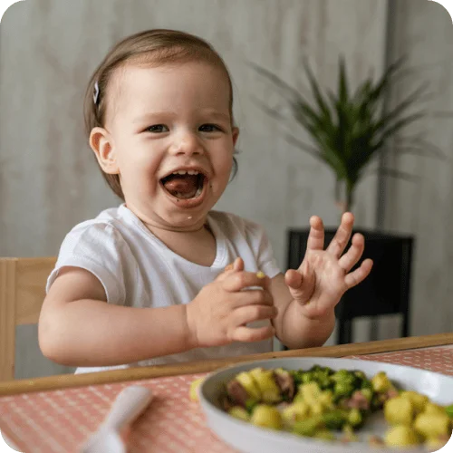 a toddler excitedly eating their dinner a toddler excitedly eating their dinner