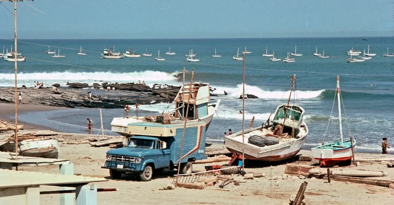 A beach with boats and truck on the shore.