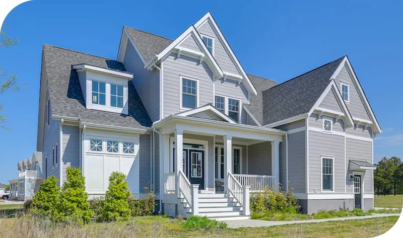Light gray coastal-style home with gabled roof, front porch, and landscaped yard.