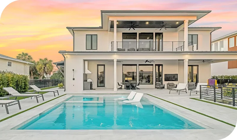 Modern contemporary home with two stories, and a backyard pool against sunset sky.