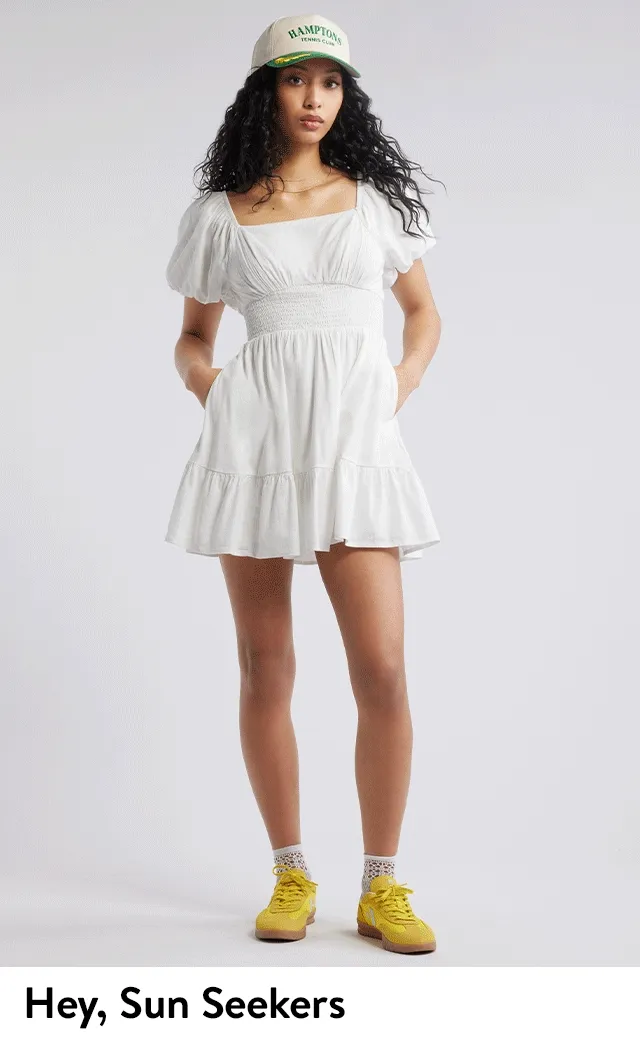 A young woman wearing a white minidress. A young woman wearing a black blouse with denim shorts.