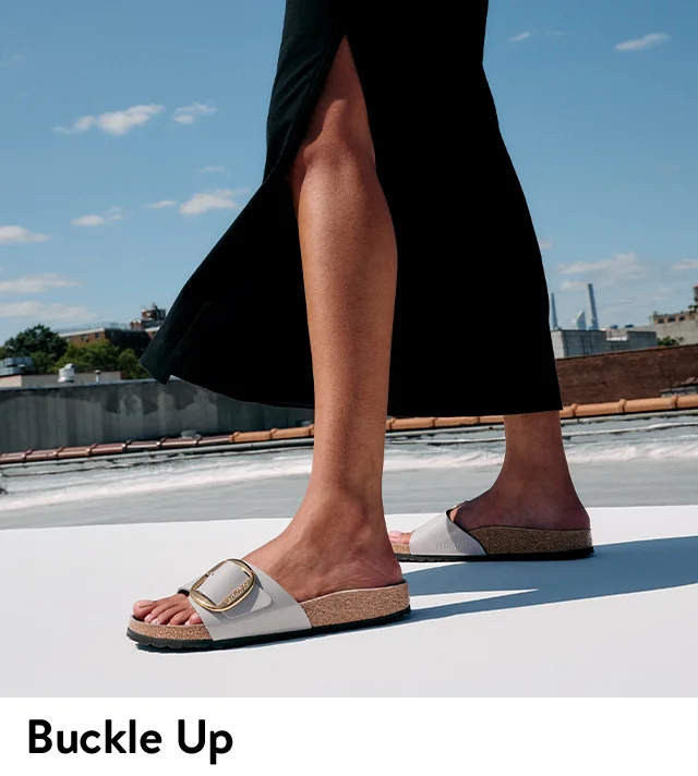 A woman wearing Birkenstock sandals with oversized buckles.