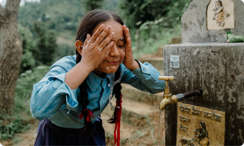 Nepalese girl washing her face and a school pipe system