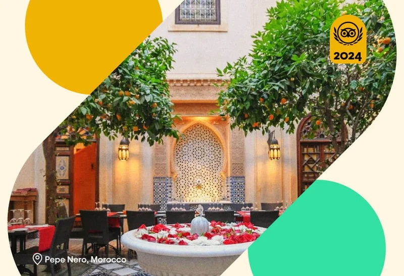 Image Description: A small fountain surrounded by tables and orange trees in the courtyard of Pepe Nero, a fine-dining restaurant in Marrakech, Morocco