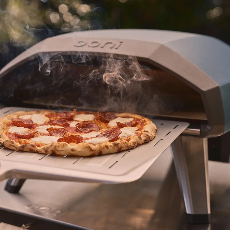 Ooni Koda 2 with a cooked salami pizza coming out