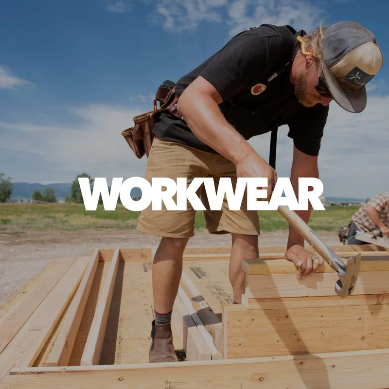 A carpenter hammers a nail on a job site. Learn more about Workwear.