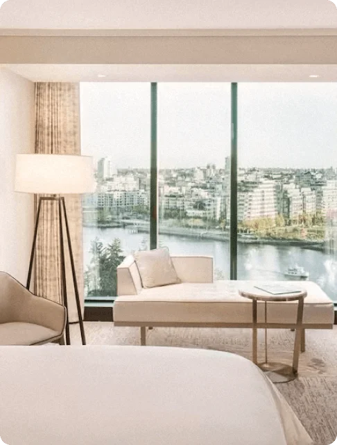 Image Description: A luxurious suite in JW Marriott Parq Vancouver with plush white furnishings and a floor-to-ceiling view of the Vancouver cityscape