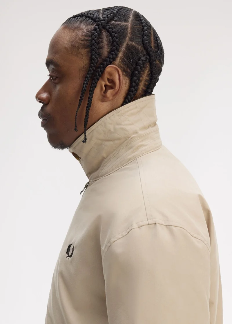 Male model with criss-crossed cornrows stands to the side and wears a beige Caban Jacket with the collar flipped up