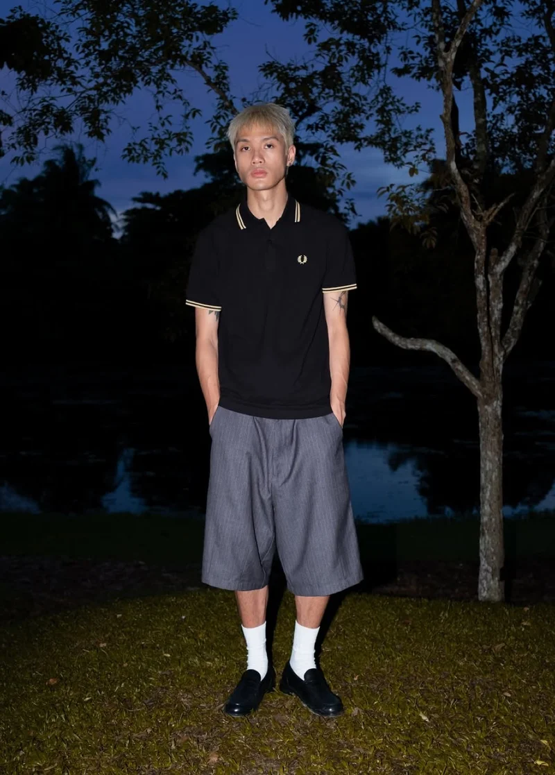 Taken from Instagram: a man stands in front of a lake at twilight and wears the Fred Perry Shirt in Black / Champagne / Champagne