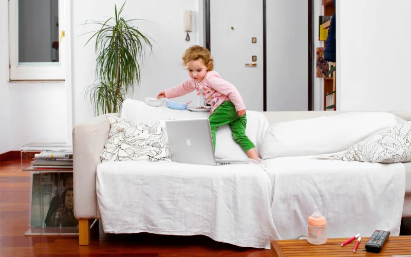 A young child watches cartoons on a laptop at home.