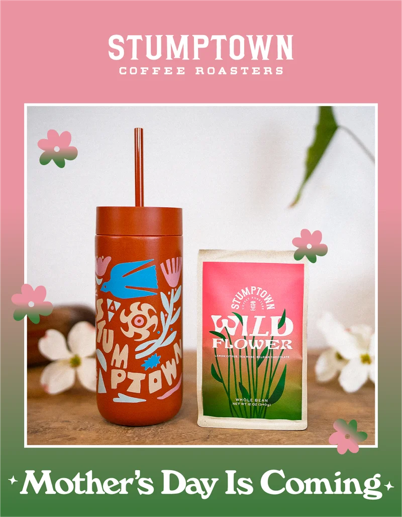 An illustrated tumbler with a straw sits beside a bag of Stumptown Wildflower coffee on a wooden surface, surrounded by soft white flowers. The image is framed with a pink border and small decorative flower graphics, with the text “Mother’s Day Is Coming” displayed at the bottom.