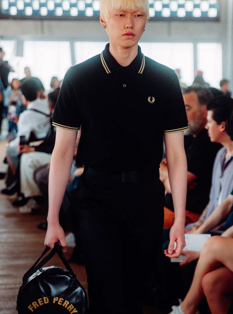 Asian model with bleach blonde hair walks the runway wearing a Fred Perry Shirt in Black Champagne Champagne