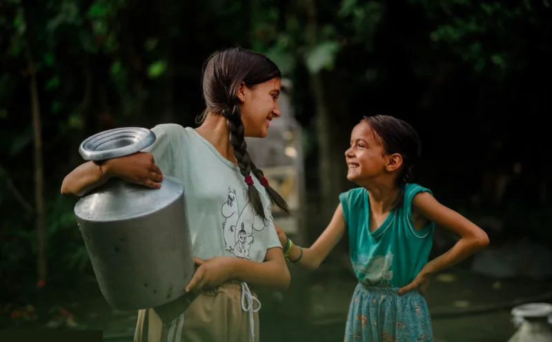 Two young girls with clean water, smiling