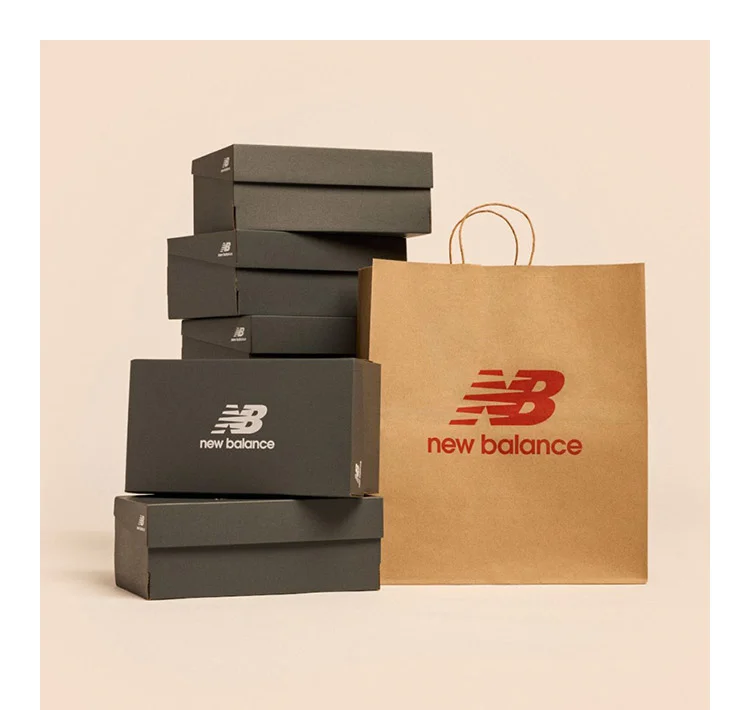 A stack of New Balance shoe boxes next to a shopping bag against a pale apricot backdrop
