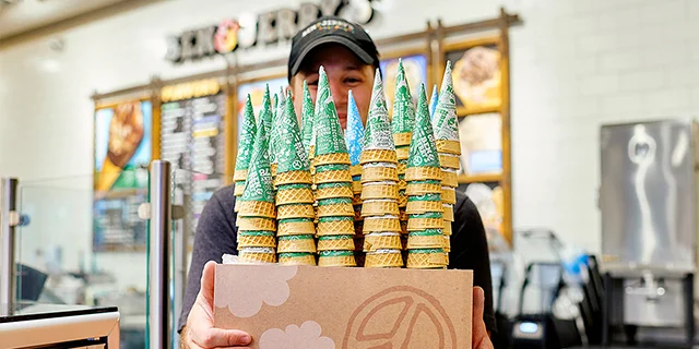 Hands grabbing ice cream cones over the counter at a Scoop Shop.