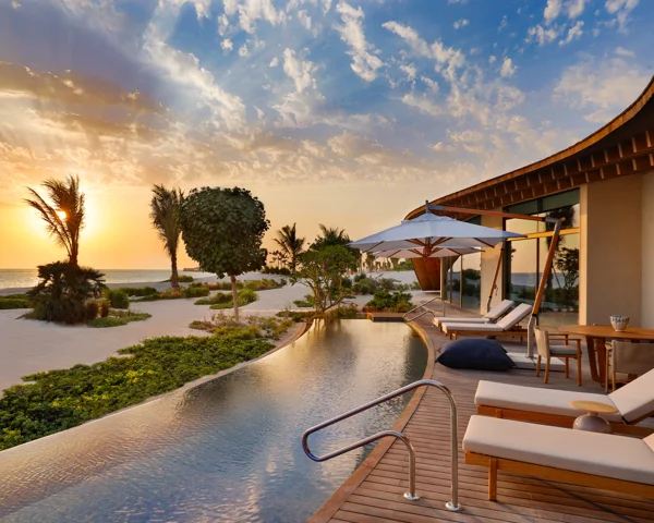 Infinity pool deck overlooks lush, tropical view at golden hour.