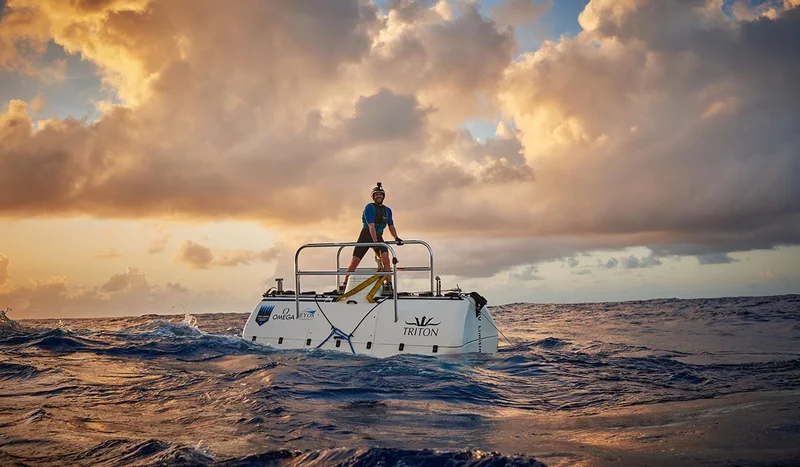 Deep sea explorer Victor Vescovo standing on the Triton submersible, surrounded by choppy waters at sunset during his record-breaking ocean dive in 2019.