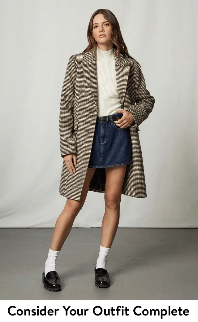 A woman wearing a turtleneck top with a houndstooth coat and denim skirt. A woman wearing a turtleneck top with a denim jacket and denim skirt.