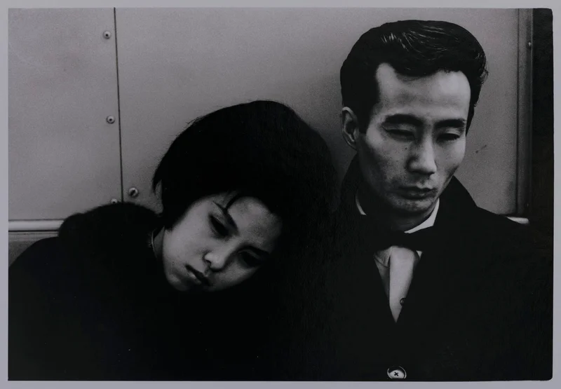 Black-and-white photograph of a woman resting her head on a man's shoulder