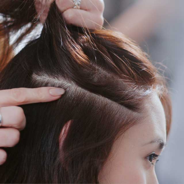 A hairstylist pointing at a client's scalp