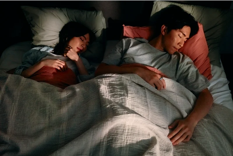 Two people sleeping in bed wearing Oura Ring