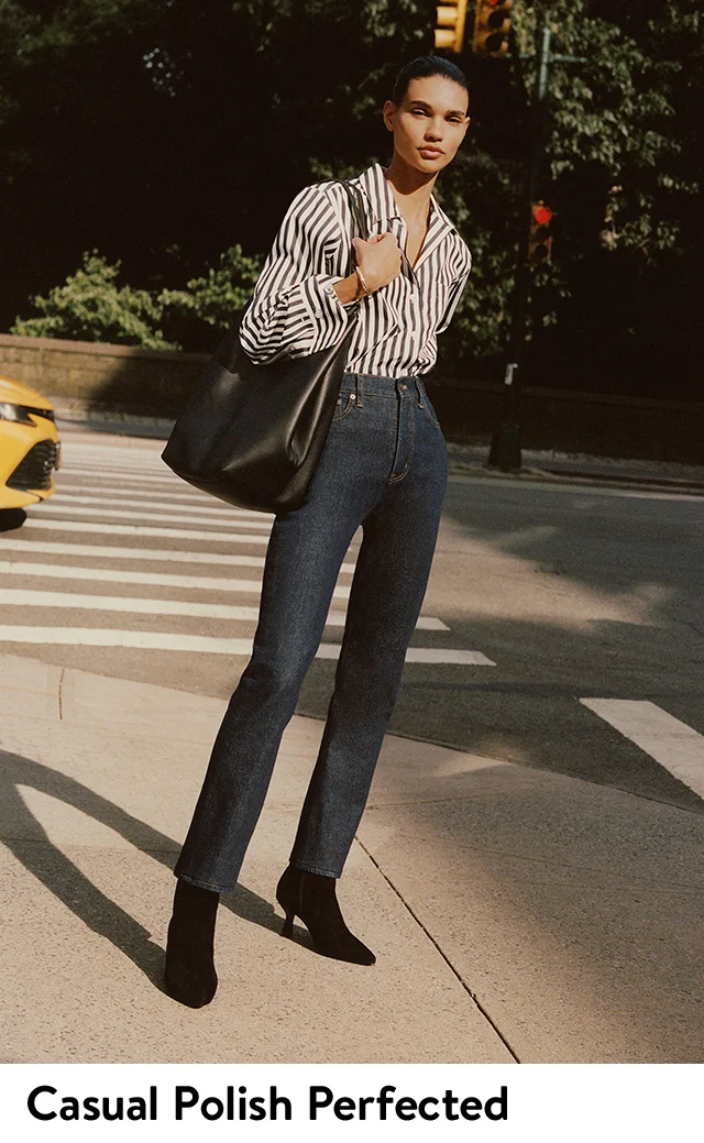 A woman wearing a striped button-down shirt with high-waist jeans.
