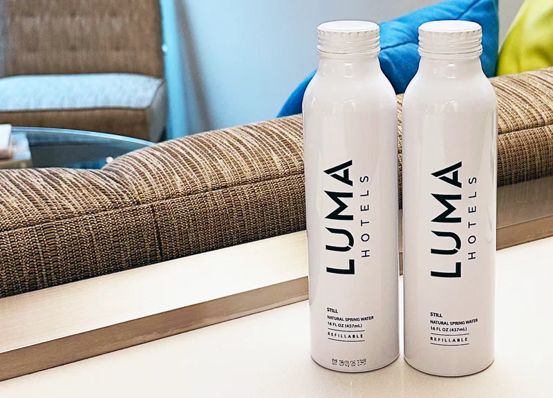 Two white aluminum water bottles with the LUMA logo in black