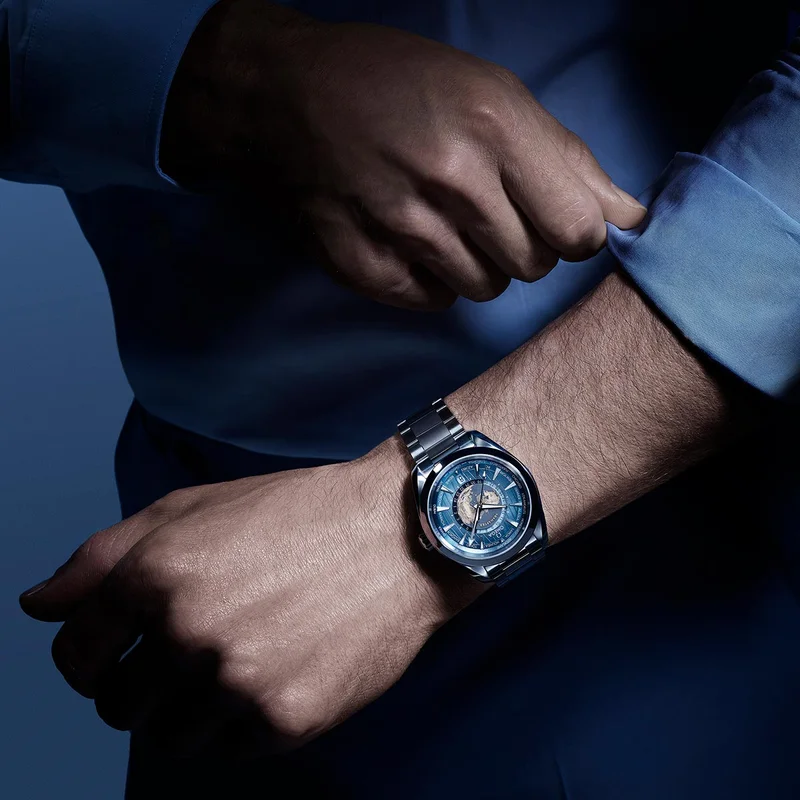 Person adjusting their sleeve showcasing an 43 mm Worldtimer watch with a Summer blue dial.