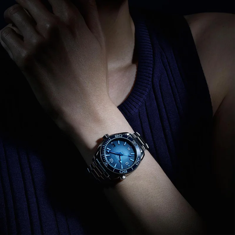Close-up of a person’s wrist wearing an Seamaster Planet Ocean 600M watch with a Summer blue dial.
