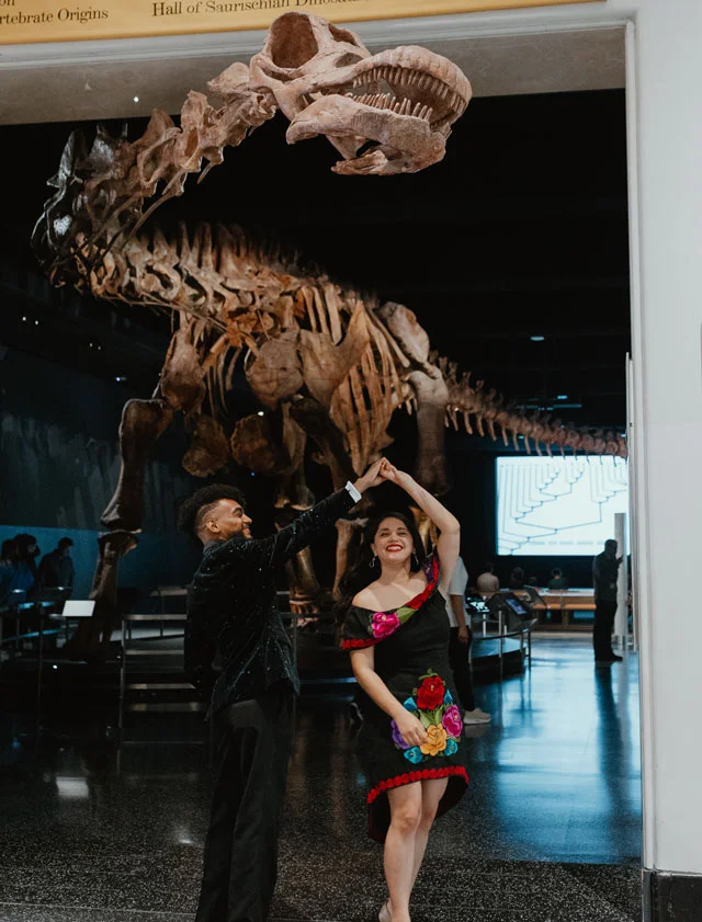 Science editor Nicholas St. Fleur and wife Miranda St. Fleur beneath the Patagotitan at the American Museum of Natural History