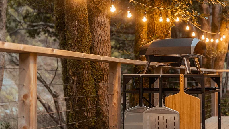 Ooni Koda 16 in a garden with fairy lights and Ooni Table and Accessories
