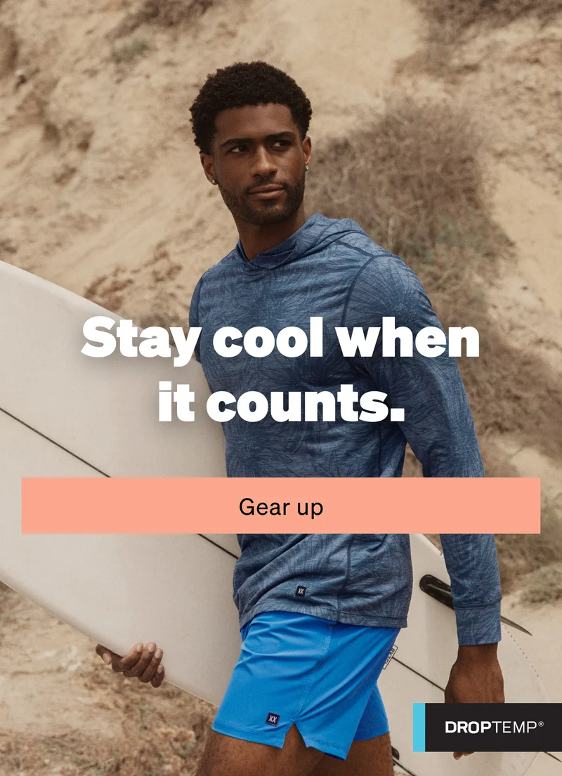 Man carrying a surfboard wearing a blue hooded top and bright blue shorts under the headline “Stay cool when it counts.” with Gear Up CTA.