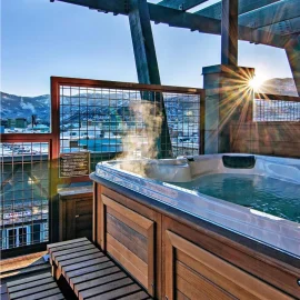 A steaming jacuzzi on a hotel balcony in the sunshine, with snowy mountains
in the background.