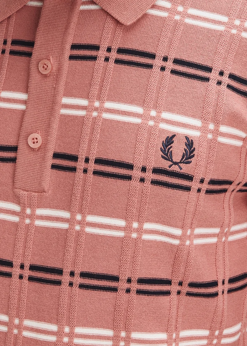 Close-up of a Mens Fred Perry Putty Pink knitted polo shirt featuring a navy and white check pattern, and embroidered laurel wreath logo